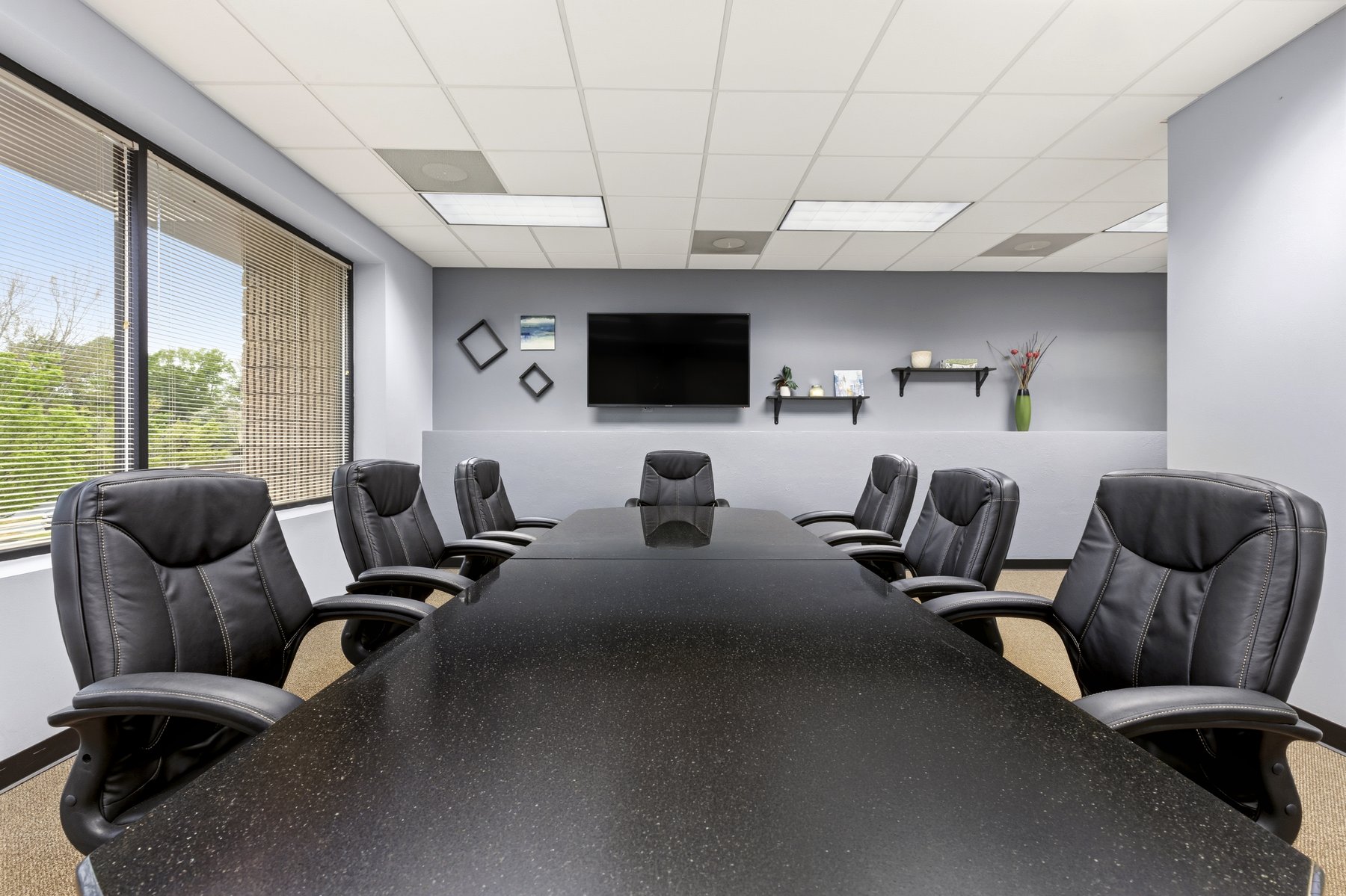 Conference room at Roswell Office Suites with wall-mounted TV and seating for eight
